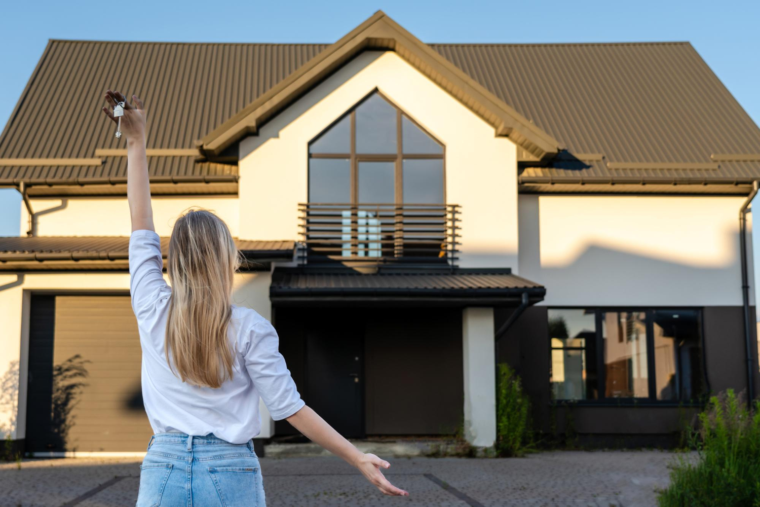 Femme heureuse se tenant avec des clés devant une maison neuve et moderne. 